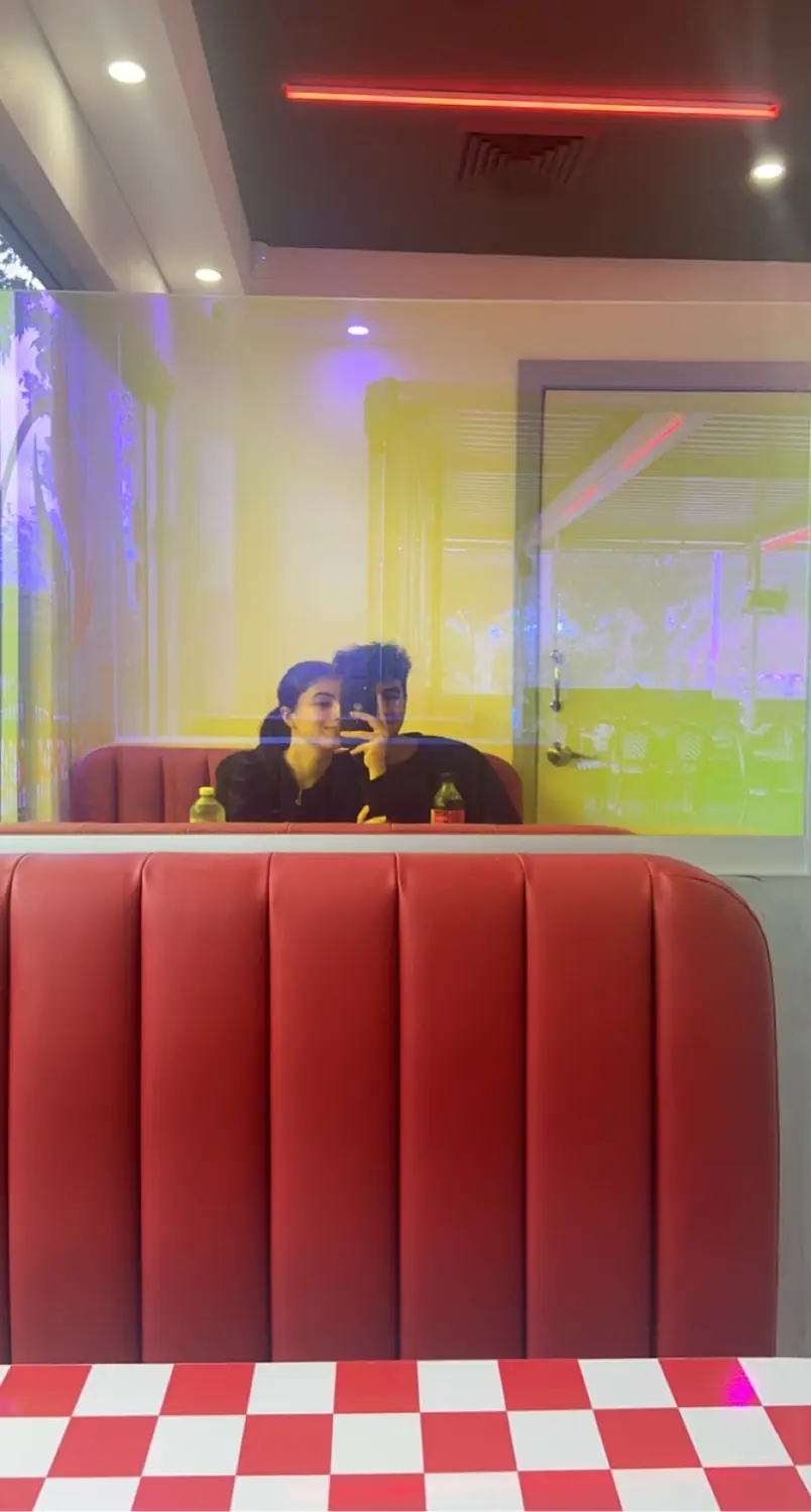 Salwa and Marchi in the mirror at a diner booth on their first date